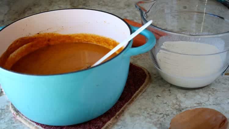 creamy carrot soup in a blue dutch oven sitting on countertop