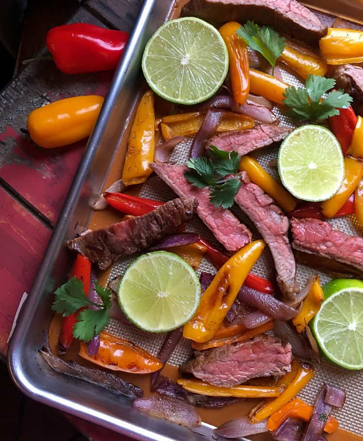 beef and peppers on sheet pan with lime slices