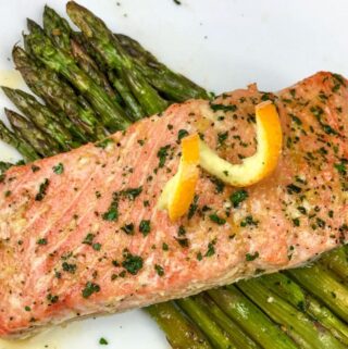 salmon plated over asparagus on white square plate