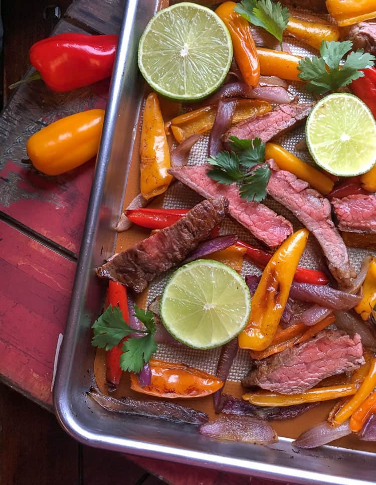 beef and peppers on sheet pan with lime slices