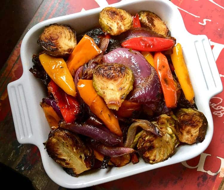 large amount of Mediterranean roasted vegetables in white square pan on a red countertop