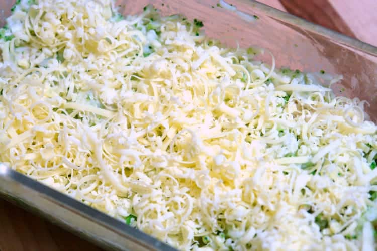Chicken, broccoli, and rice casserole in a casserole dish before baking covered with cheese