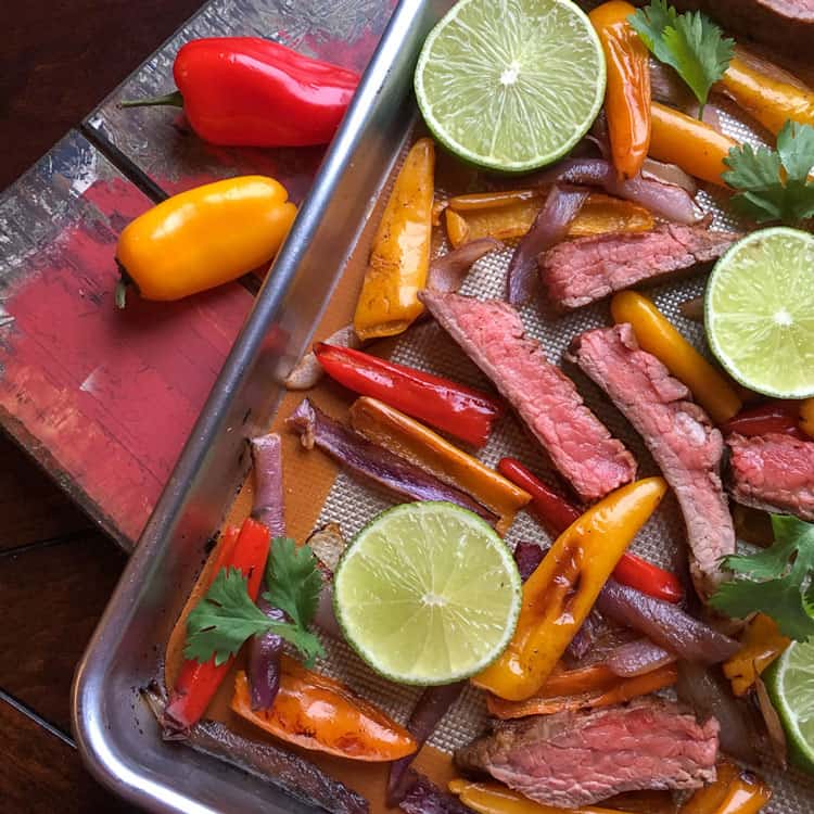 beef and peppers on sheet pan with lime slices