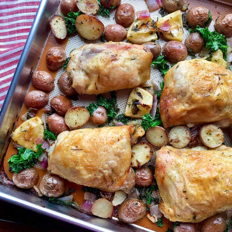 view of herb-roasted chicken on a sheet pan with roasted potatoes and roasted thyme