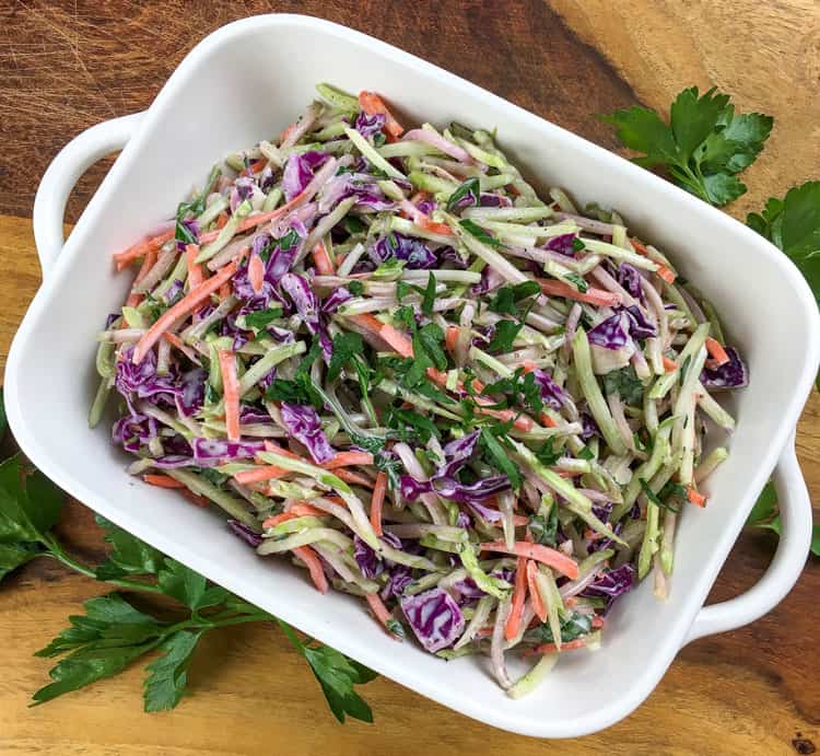 overhead view of white serving dish containing keto slaw on top of green leaves