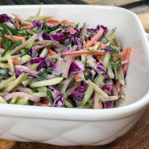 white serving dish containing colorful broccoli keto slaw