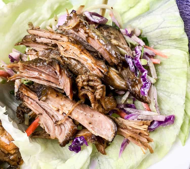 closeup of single easy keto lettuce wraps with strips of pulled pork on top of a piece of iceberg lettuce