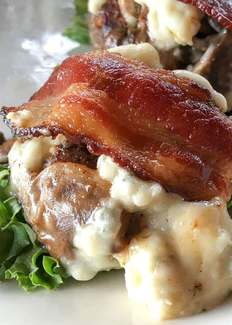 closeup of keto hamburgers with bacon on top over cheese and mushrooms