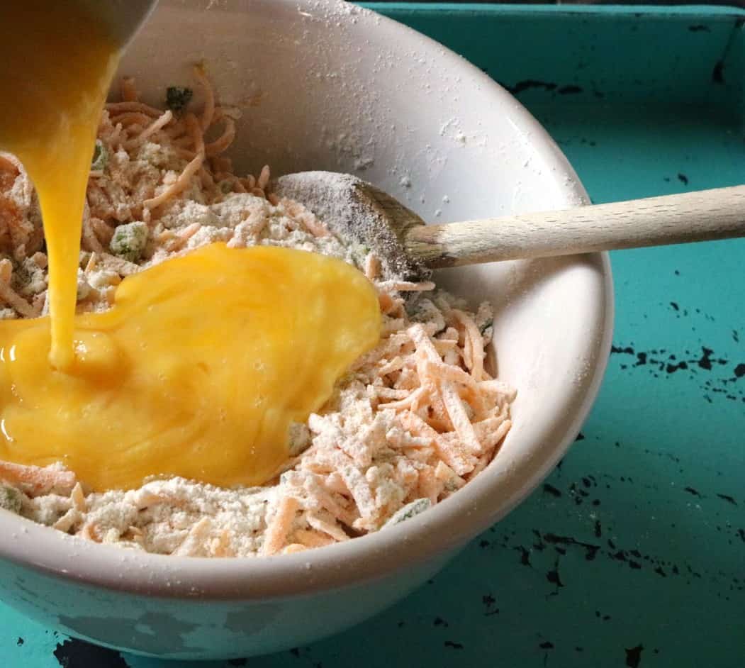 Mexican Corn Bread Step 4 adding eggs to mix in white bowl.