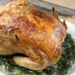 Permalink to: Keto Chicken with Garlic and Herbs keto chicken sitting on herbs on a white plate on a countertop