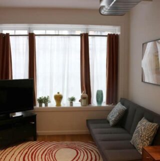living room with futon couch and white room width windows