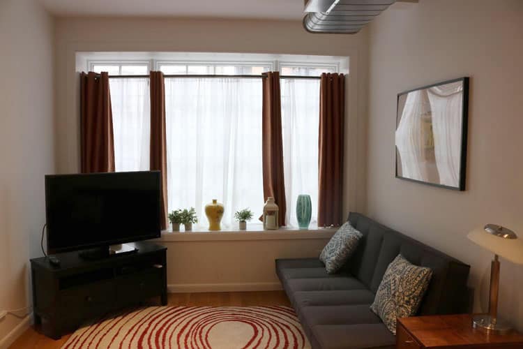 living room with futon couch and white room width windows