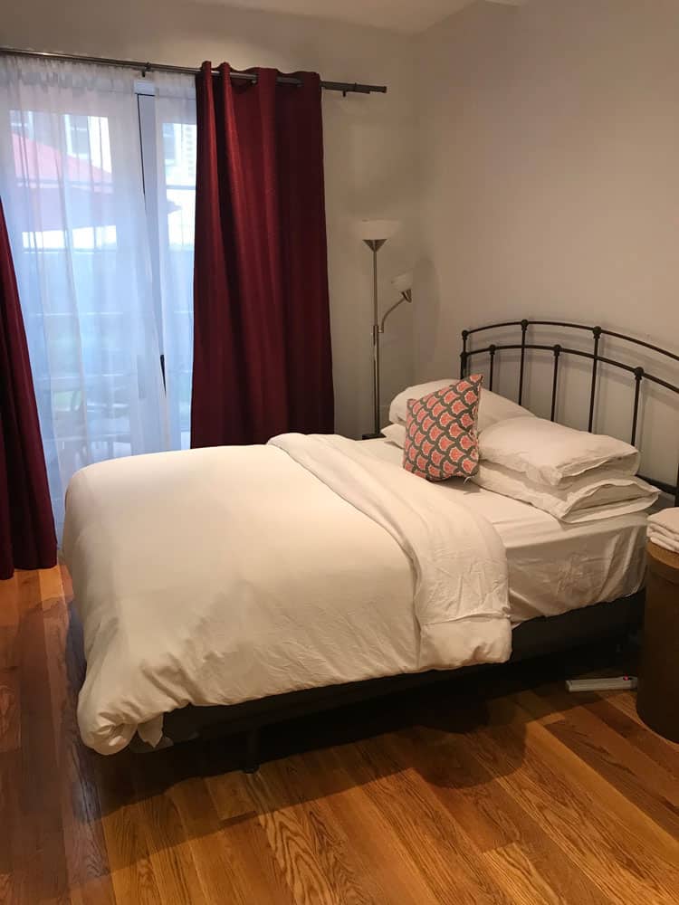 queen size bed with white down comforter on wood floor