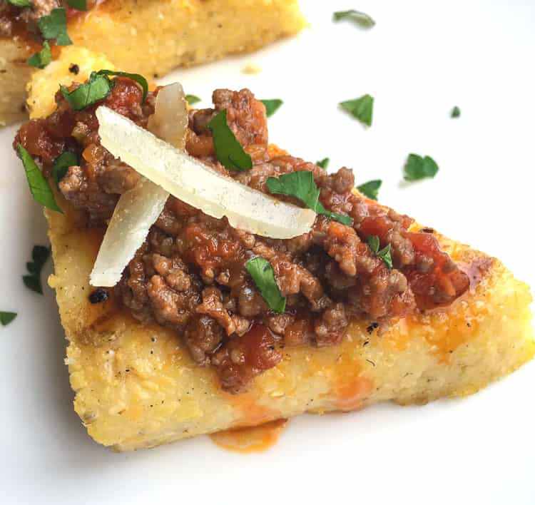 closeup of polenta crostini with meat and onions on top