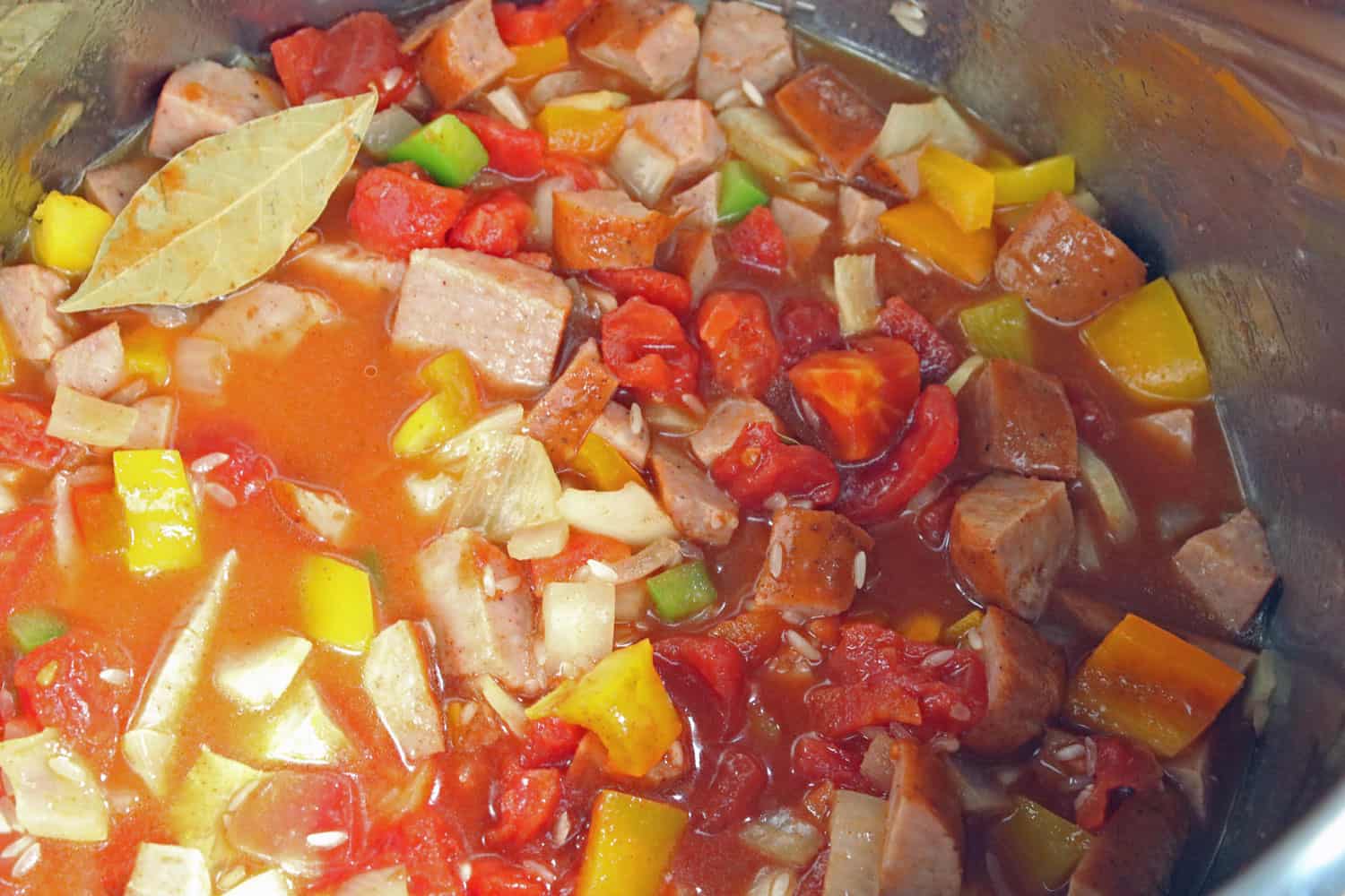 sausage and rice recipe being cooked in chicken stock 