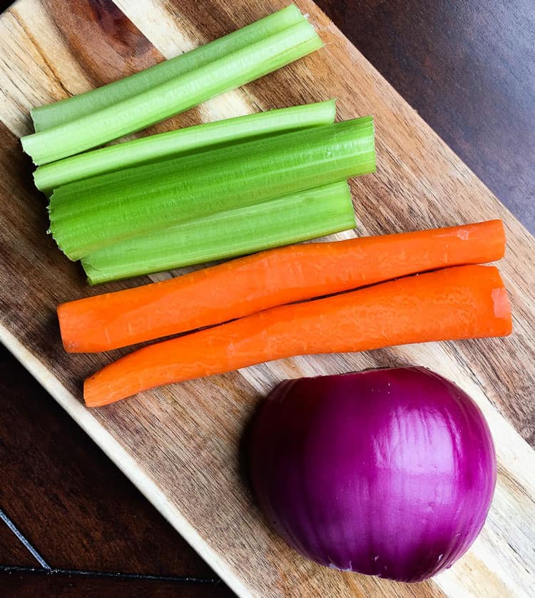 chopped vegetables on a cutting board including celery, carrots, and red onion ready to be used in sausage ragu