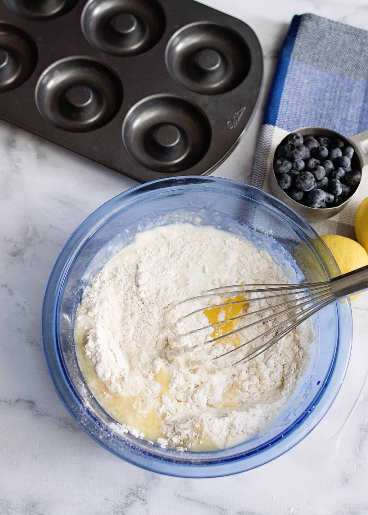 blue mixing bowl with flour and egg being mixed with whisk