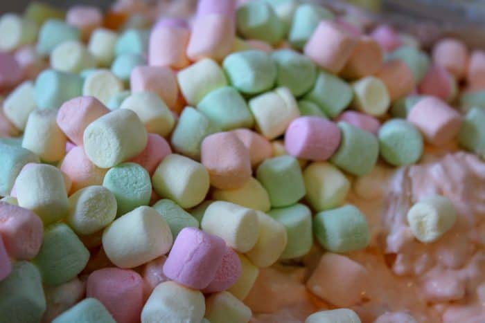 mixing mini marshmallows into orange fluff salad