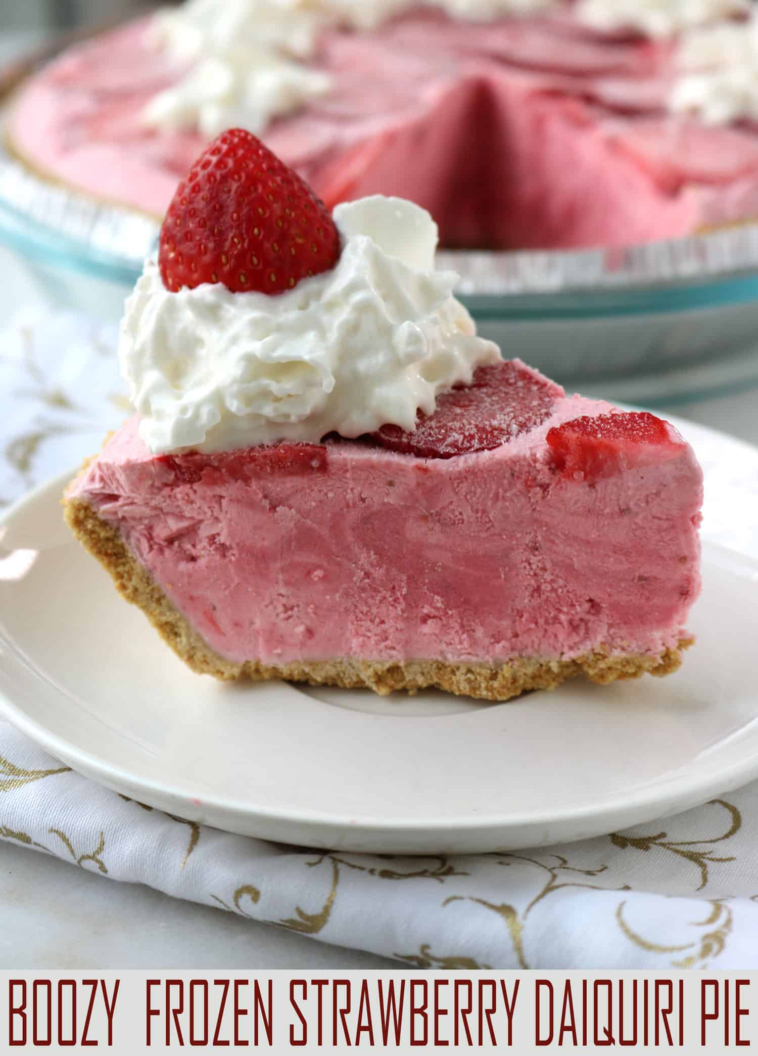Boozy Frozen Strawberry Daiquiri Pie is a fun and festive no-bake treat, perfect for summer. It's a delicious frozen cocktail served on a plate! #strawberrydesserts #boozydesserts #pie #nobake