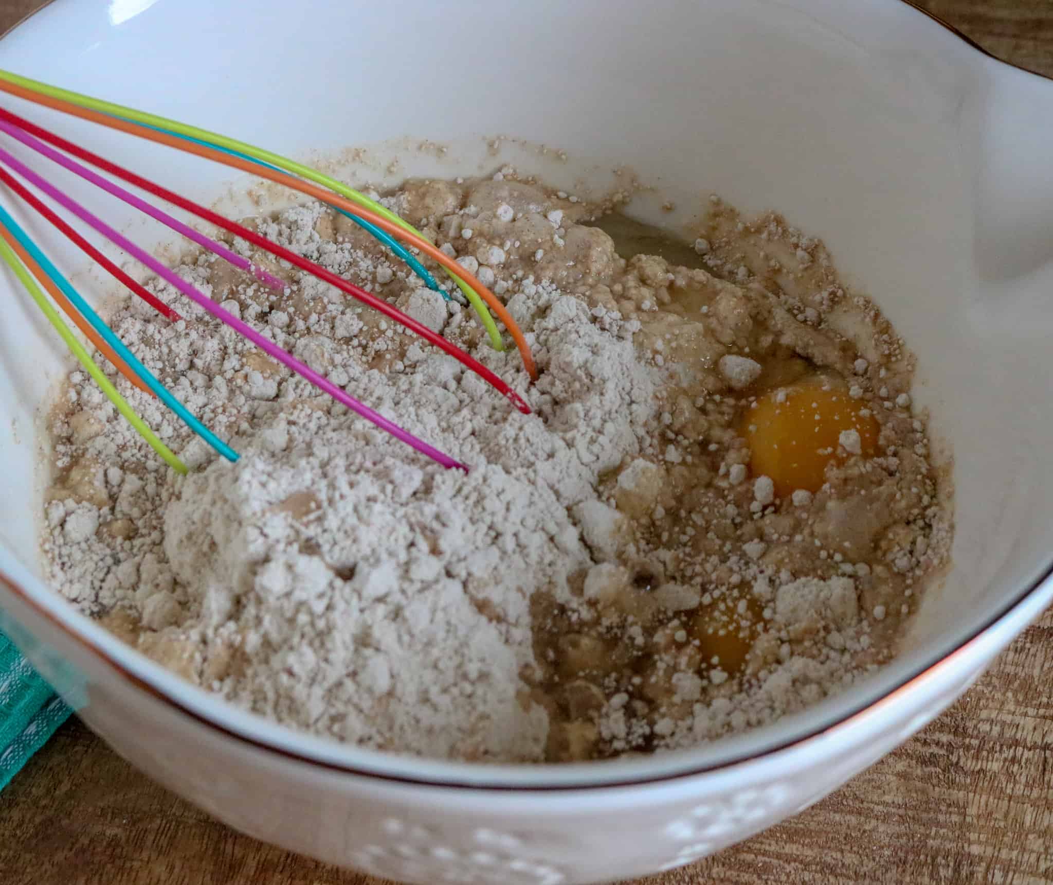 Spice cake mix, eggs, water and vegetable oil in a bowl being mixed with a whisk.