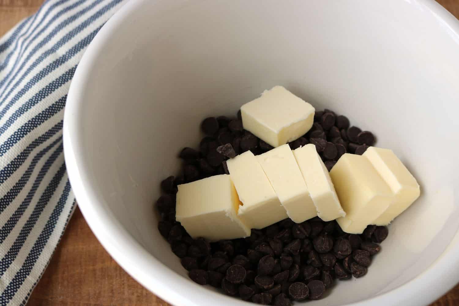 chocolate chips and slices of butter in a white bowl