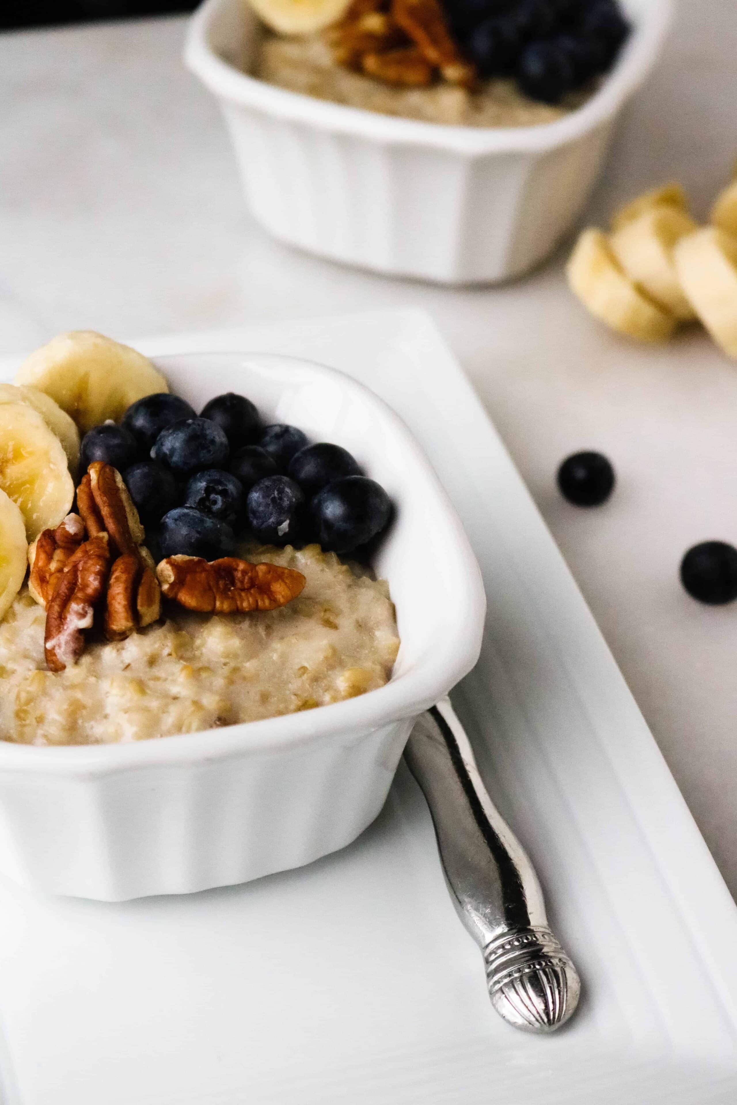 Instant Pot steel cut oatmeal served in a white bowl and topped with blueberries, sliced banana, and pecans