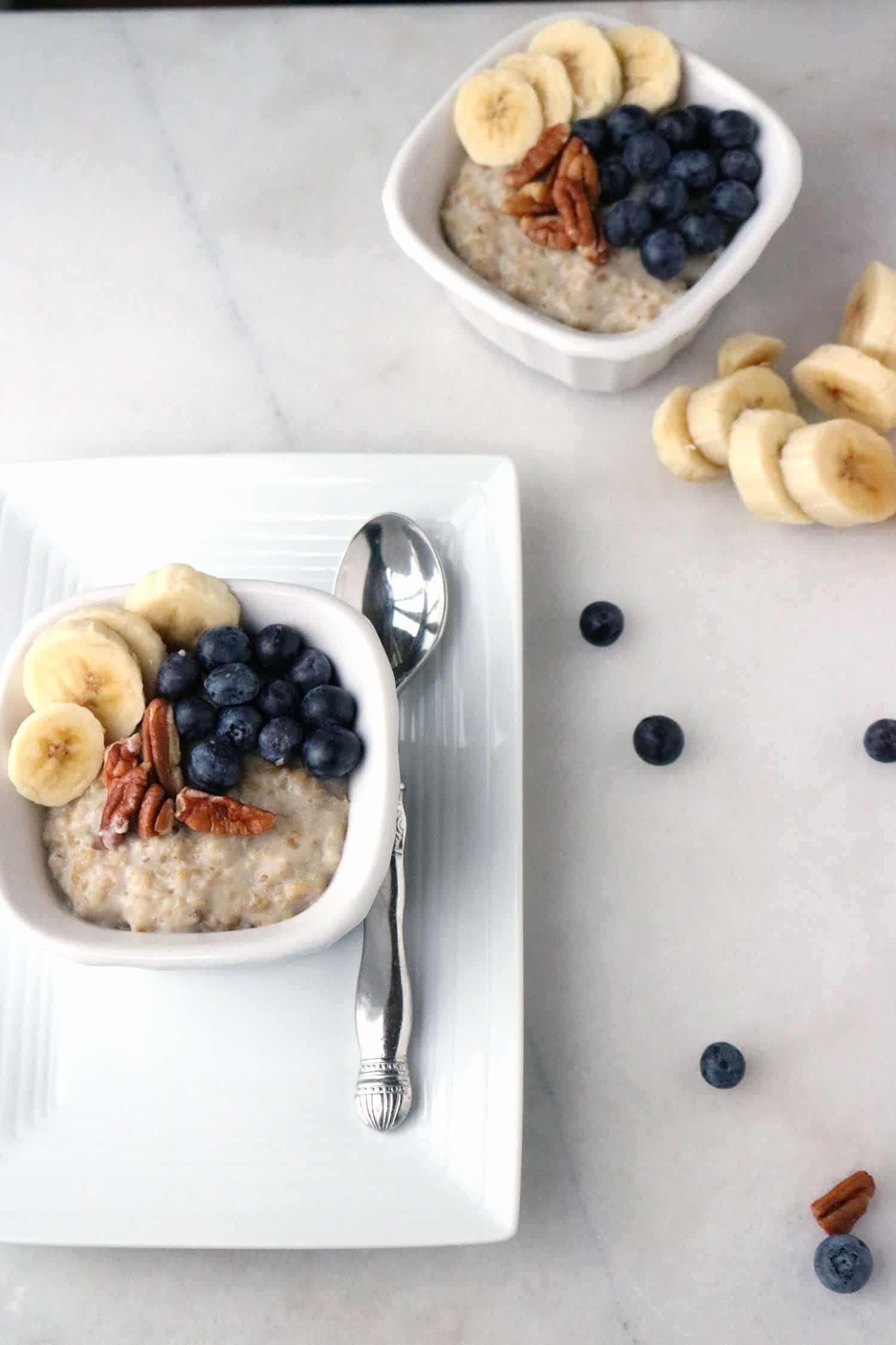 Instant Pot steel cut oatmeal served in a white dish and topped with blueberries, sliced banana, and pecans