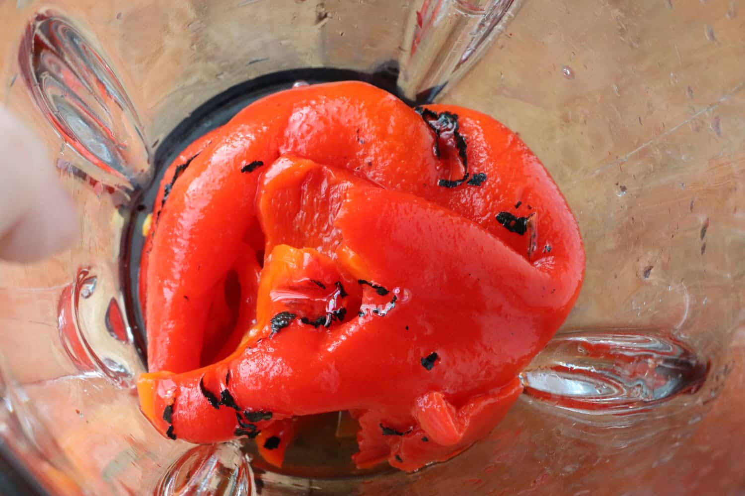 looking into a clear food processor at roasted red pepper dip