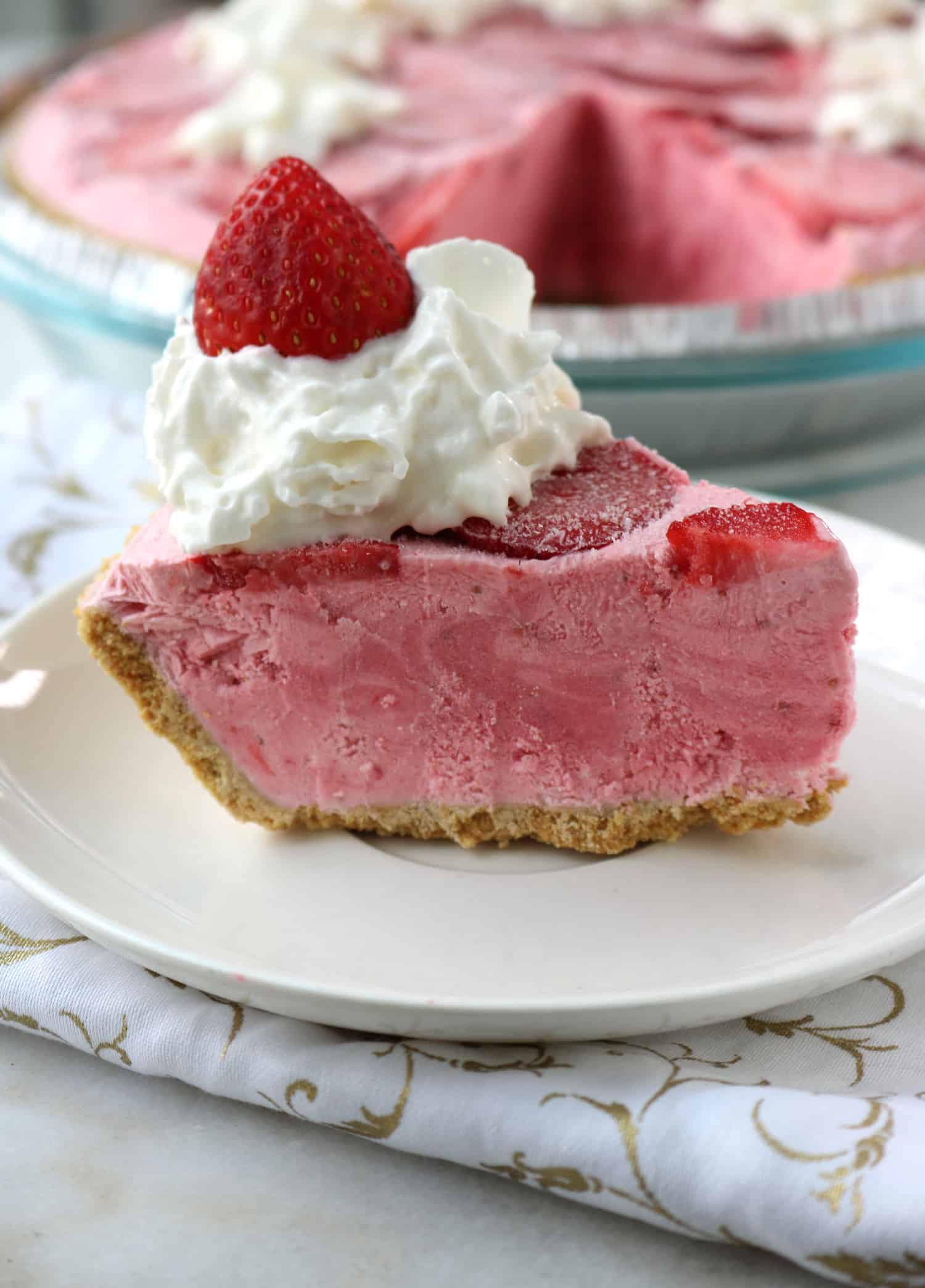 a slice of boozy frozen strawberry daiquiri pie served on a white plate