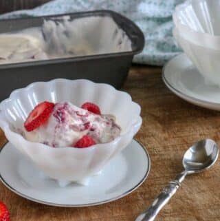 A serving of Berry Pie No-Churn Ice Cream in a white scalloped edged bowl next to a silver spoon