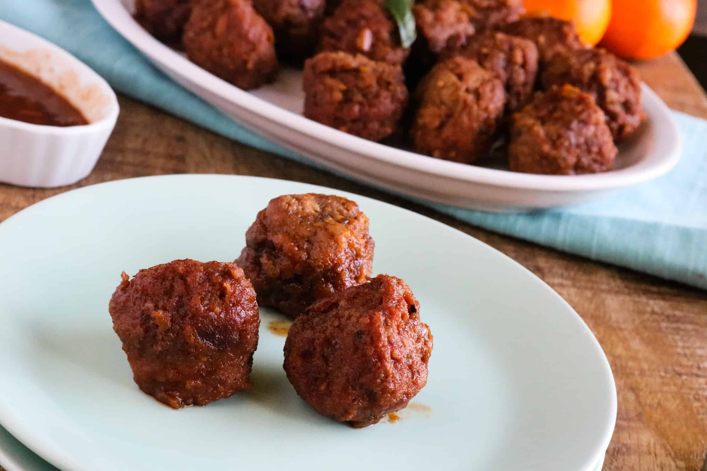 Three meatballs from the Instant Pot Orange BBQ Meatballs Recipe served on a light blue plate