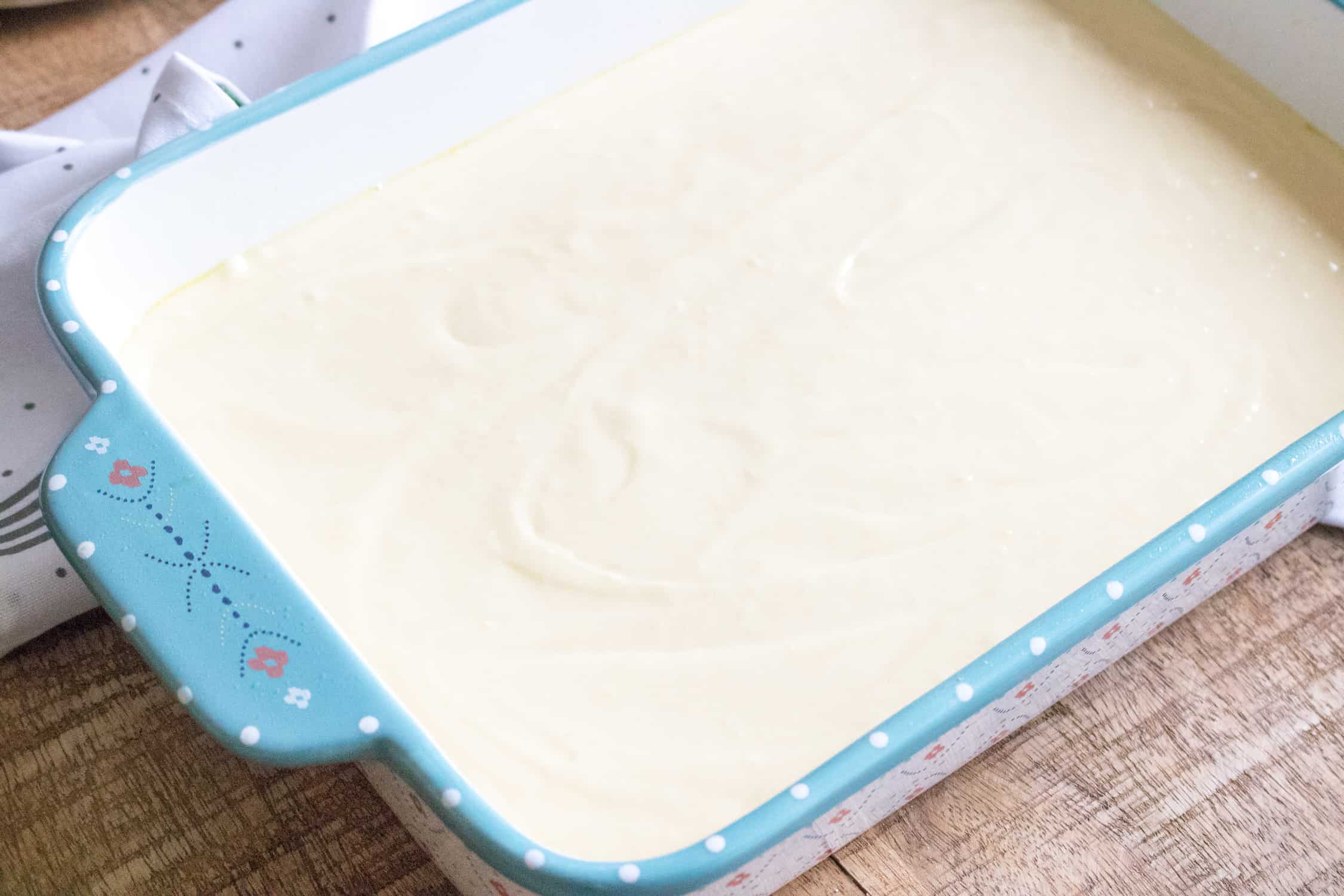 top-down view of the unbaked white cake in a blue print baking dish