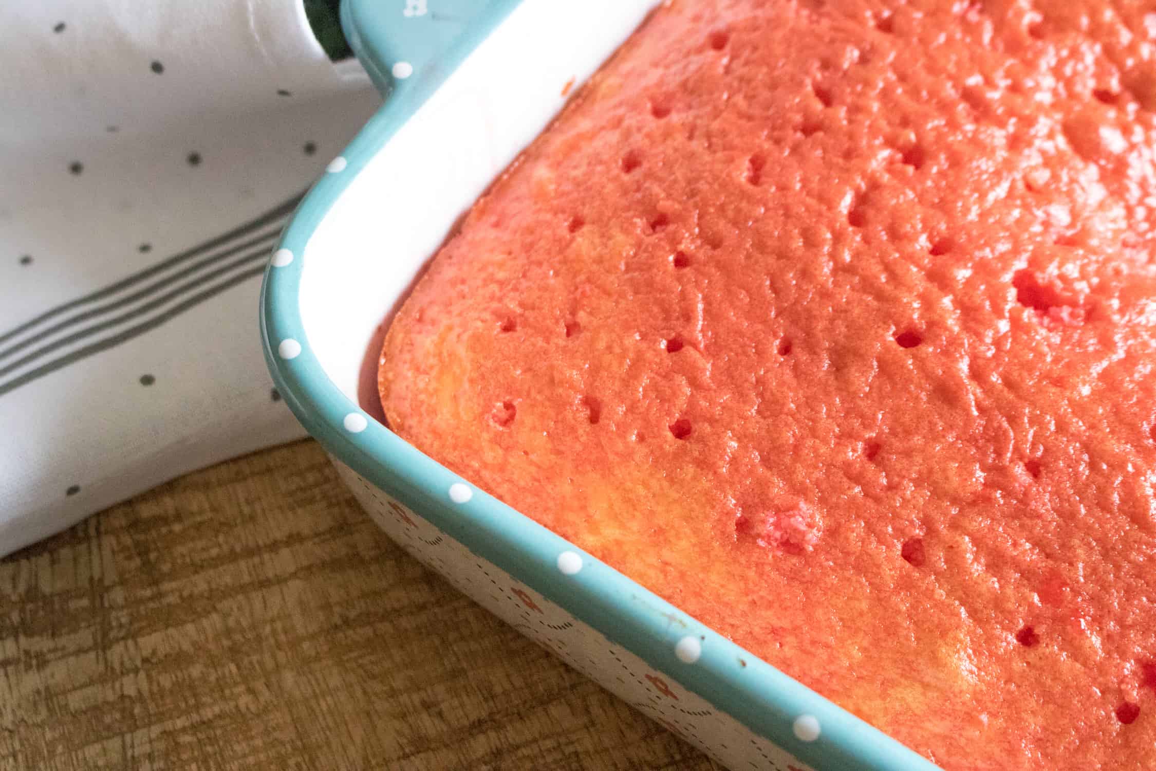 close-up of the white sheet cake with strawberry gelatin mixture soaking into the top