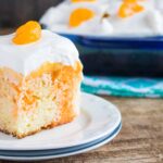 A slice of Orange Creamsicle Poke Cake served on a white dessert plate
