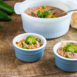 Two portions of Instant Pot Refried Beans served in light blue ramekins