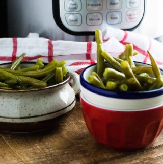 Instant Pot Green Beans served in red and white bowls next to a red checked cloth napkin