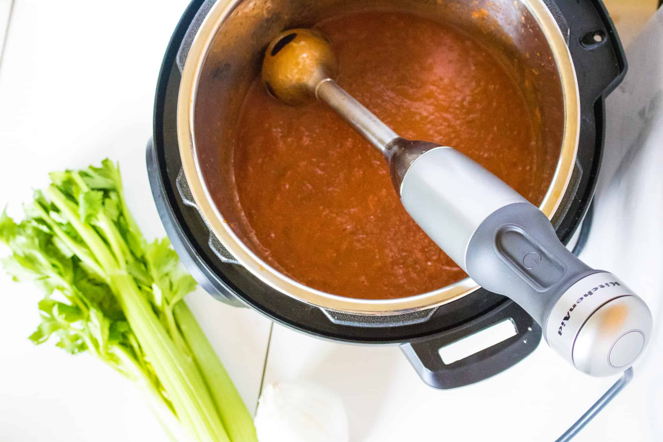 top-down view of cooked Sauce being puréed with an immersion blender inside the instant pot
