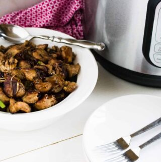 Instant Pot Jerk Chicken in a white serving bowl and garnished with green onions