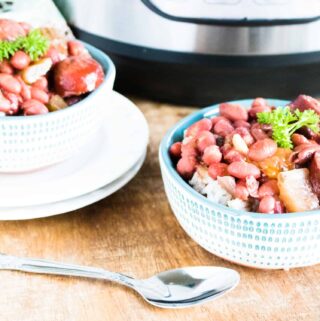 Two portions of Instant Pot Red Beans and Rice served in white bowls next to the Instant Pot and a silver spoon