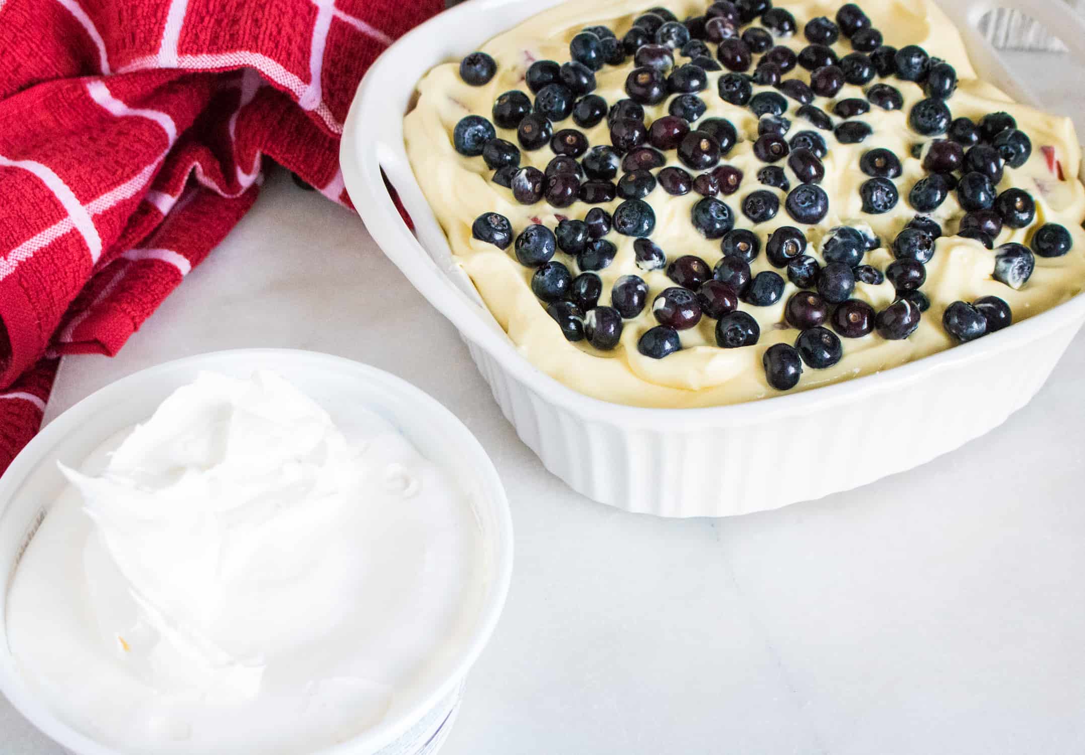 Layer of pudding and blueberries added with whipped topping on the side