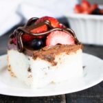 Chocolate Ganache Poke Cake with Berries sliced and served on a white dessert plate