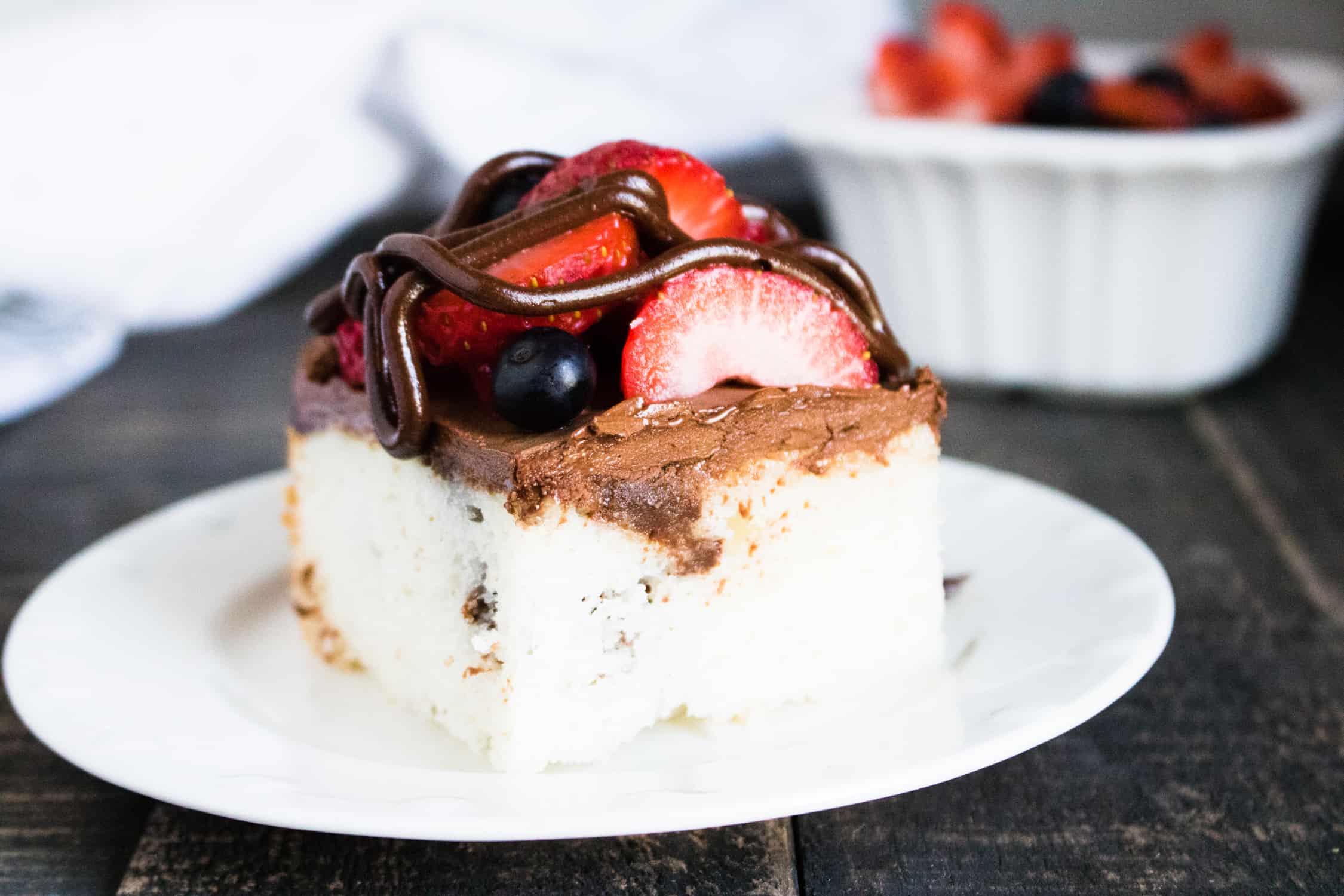 one slice of chocolate ganache poke cake with berries served on a white plate 