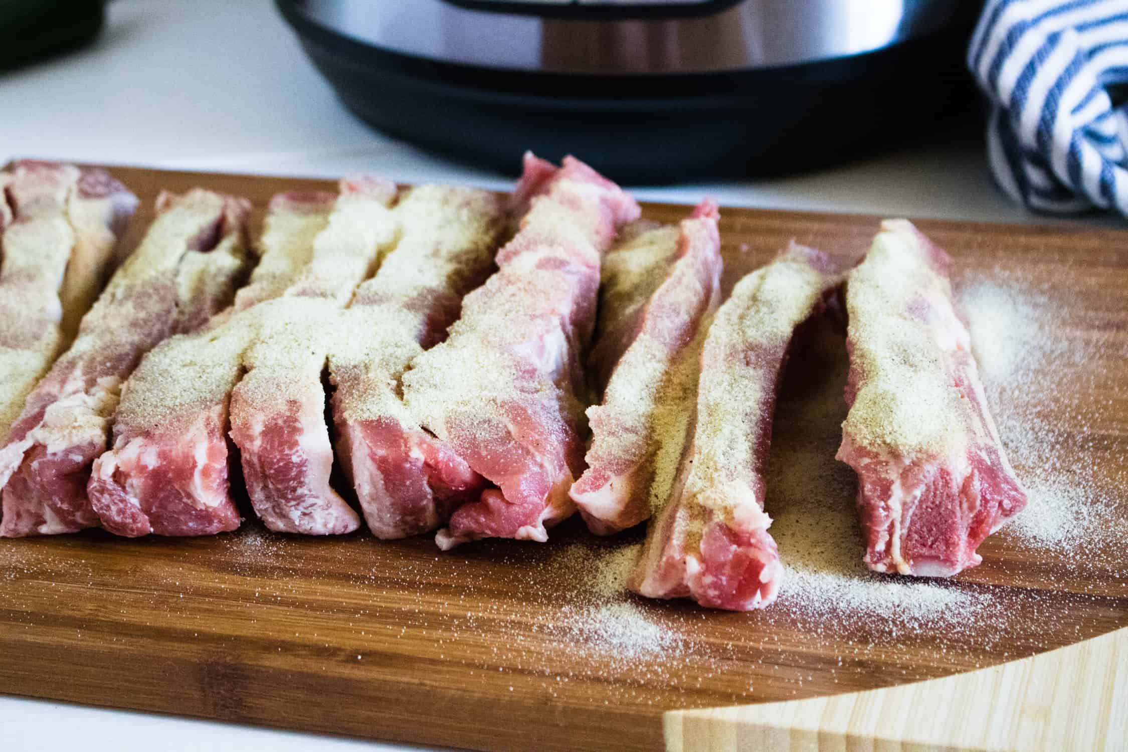 raw ribs for instant pot rib tips on wooden cutting board with seasoning on them