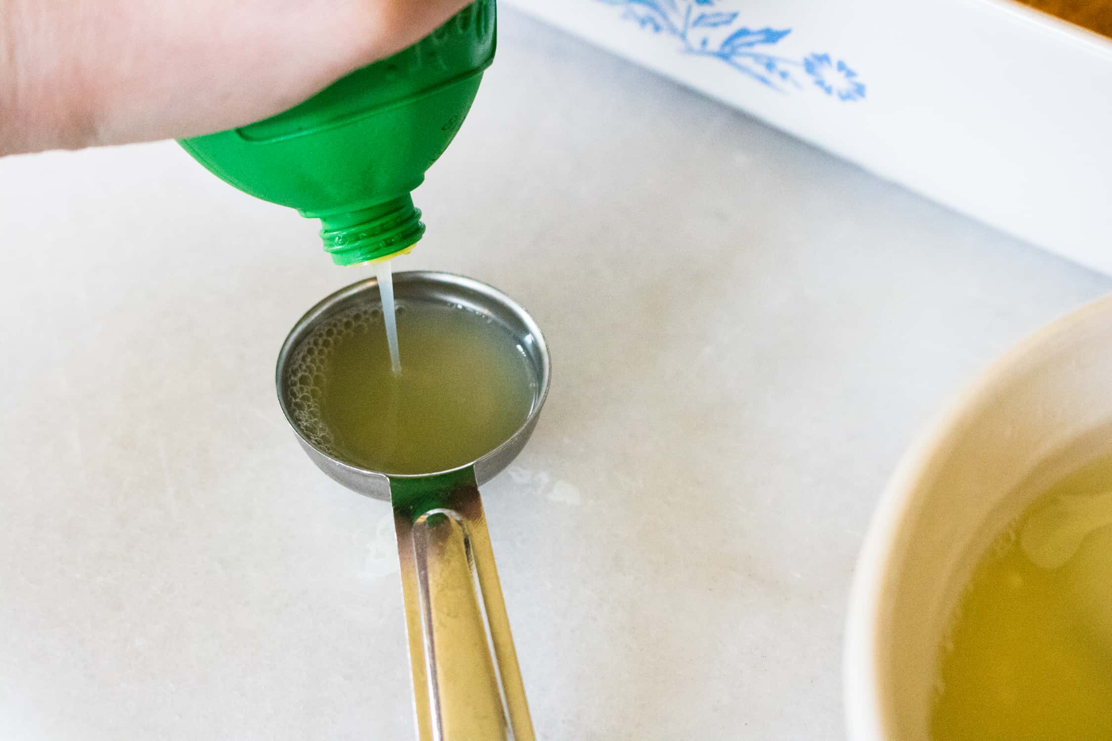 Lime juice being poured into a measuring spoon for the poke cake topping