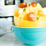 Permalink to: Instant Pot Spaghetti Squash Completed Instant Pot Spaghetti Squash served in a blue bowl and topped with sliced sherry tomatoes and crumbled cheese