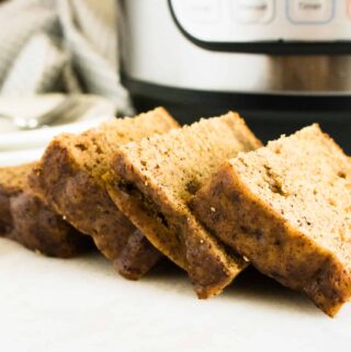 Slices of Instant Pot Banana Cake on a wood cutting board in front of the Instant Pot