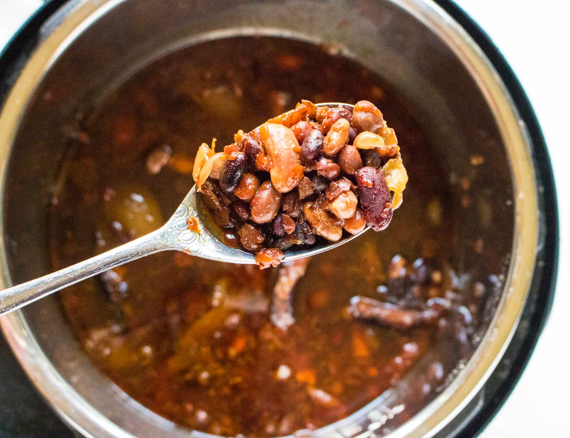 Cooked 7 Bean BBQ Instant Pot Baked Beans in an instant pot with a spoonful of beans stopped out