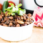 Instant Pot 7 Bean BBQ Baked Beans served in a white ceramic dish and garnished with parsley