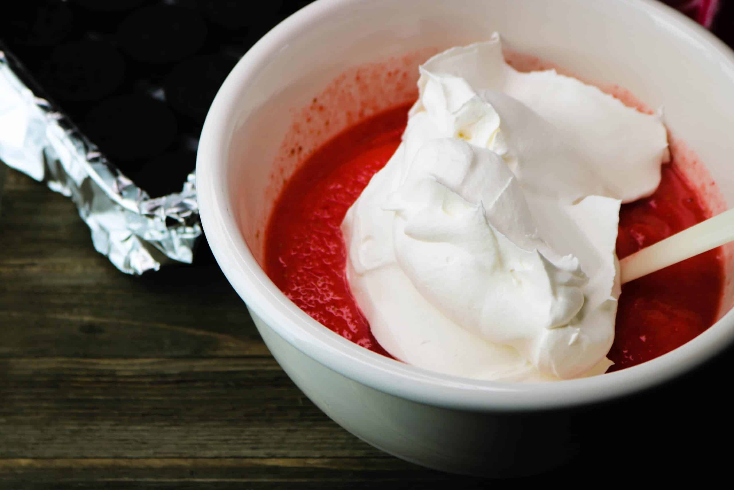 Blended strawberry dessert mixture in a white bowl with whipped cream on top