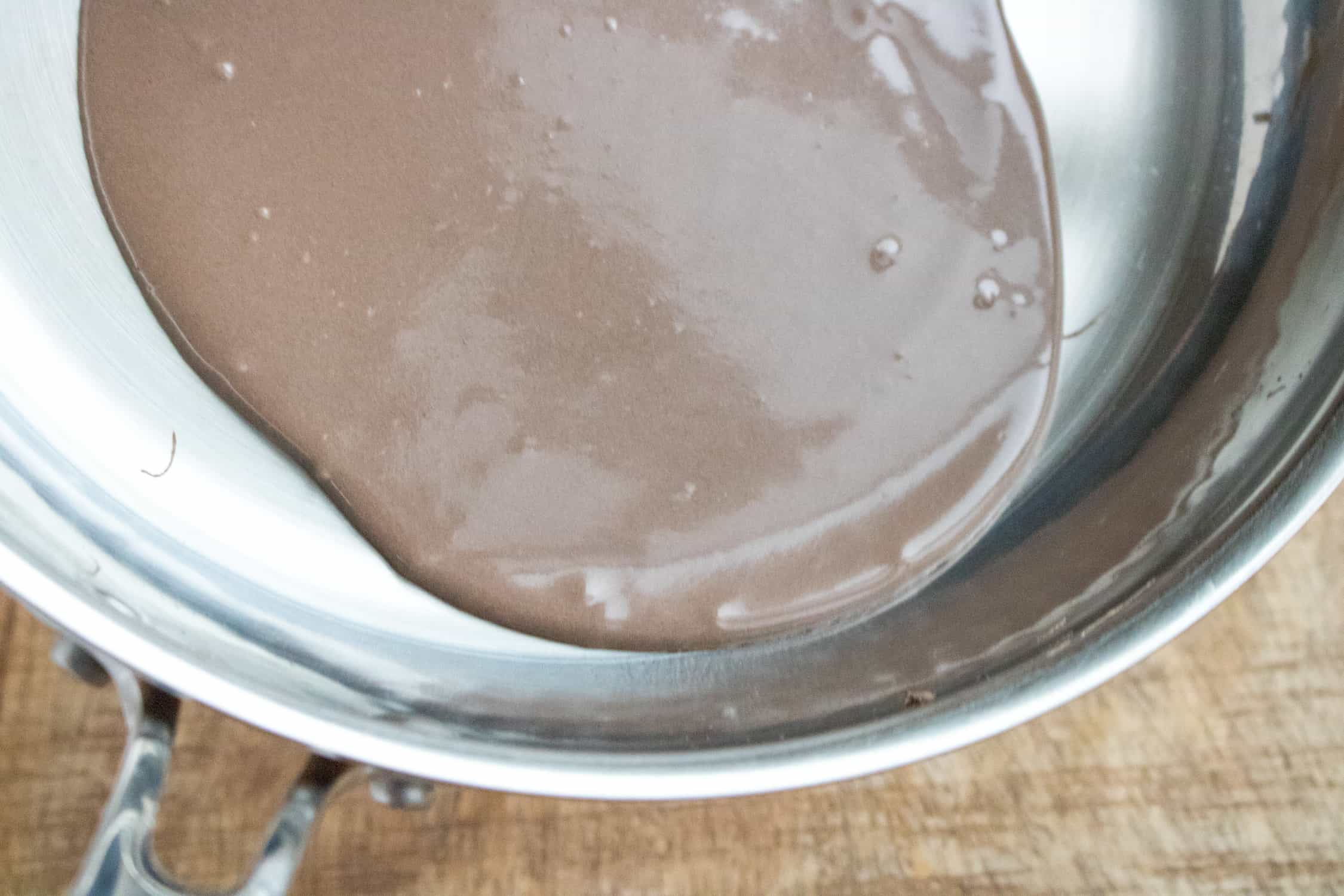 chocolate dessert crepes batter poured into a pan and being spread out to the sides